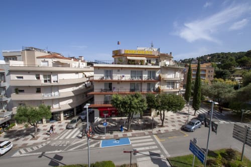Hotel El Sol II en Tossa de Mar con plaza, edificios coloridos, árboles y entorno de pueblito costero mediterráneo