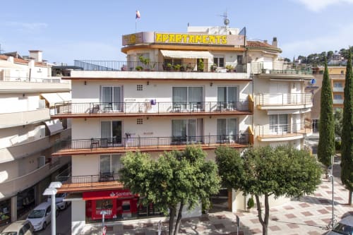 Apartamentos El Sol II en Tossa de Mar con señalización amarilla, balcones y tiendas en planta baja
