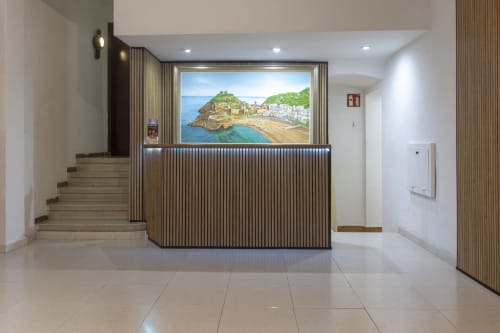 Recepción moderna del hotel El Sol II Tossa de Mar con arte de pueblo costero y mostrador de madera