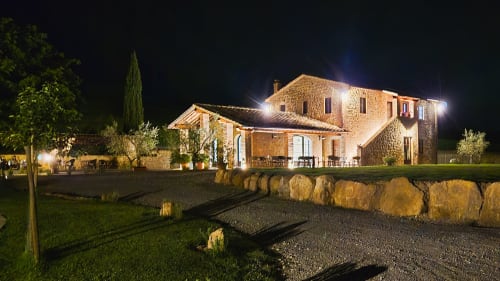 Agriturismo Marinello a Pienza, Toscana di notte - casale illuminato con architettura in pietra, giardini e fascino rustico