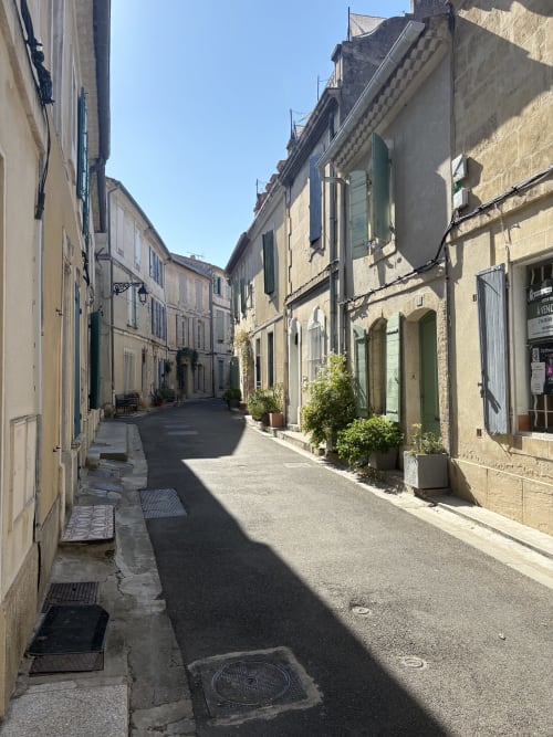 Charmante ruelle d'Arles aux bâtiments historiques en pierre et volets verts à la Conciergerie Maurin