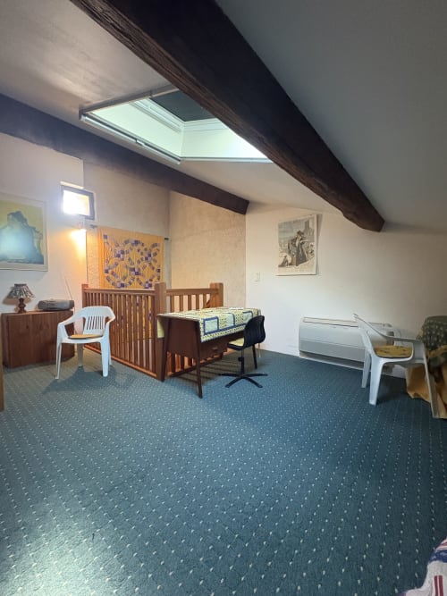 Chambre mansardée à la Conciergerie Maurin à Arles avec verrière, poutre apparente, lit bébé, bureau et tapis bleu