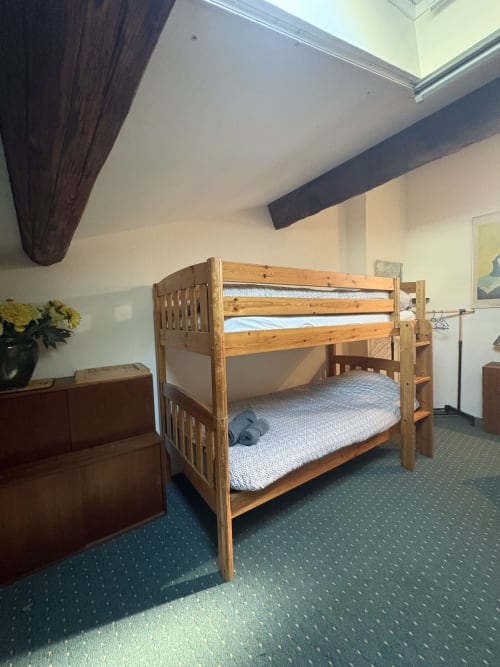 Lit superposé en bois avec matelas gris dans la chambre mansardée de la Conciergerie Maurin, Arles