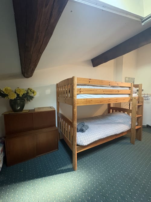 Lit superposé en bois dans la chambre Conciergerie Maurin, Arles, avec commode et fleurs jaunes