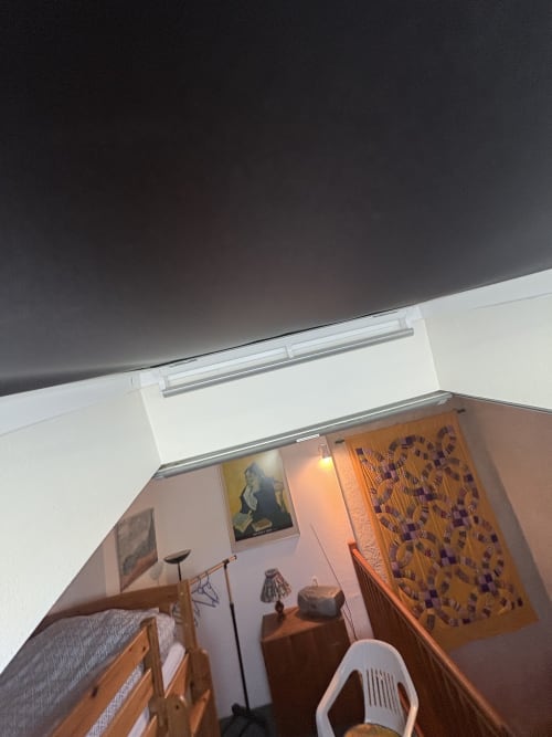 Chambre douillette à la Conciergerie Maurin à Arles avec mobilier en bois, murs blancs et œuvres décoratives