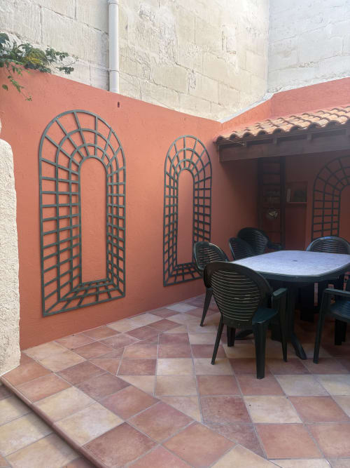 Terrasse de la Conciergerie Maurin à Arles avec table de salle à manger, chaises noires et treillis décoratif mural