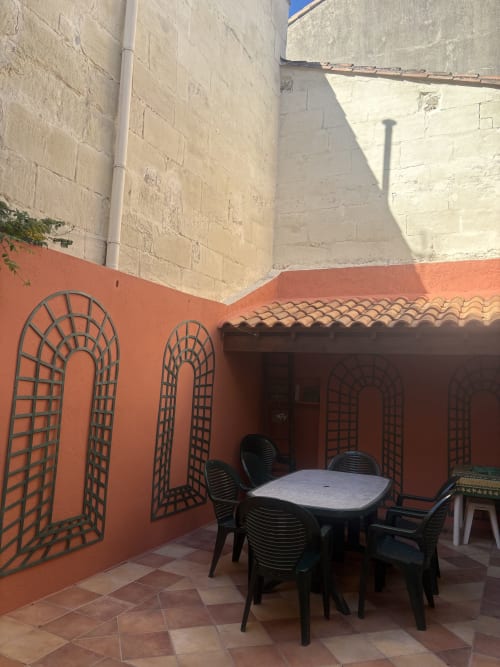 Cour pavée orangée avec table et chaises de restaurant à l'hôtel Conciergerie Maurin à Arles, France