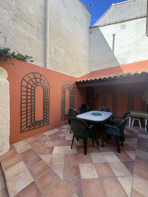 Terrasse de cour à la Conciergerie Maurin avec table à manger, chaises, carrelage en terre cuite et murs treillis ornementaux voûtés