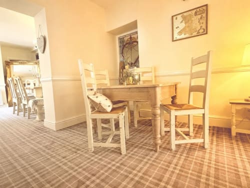 Bright dining area in The Usk Guest House apartment with wooden table, white chairs, and mountain views in Brecon