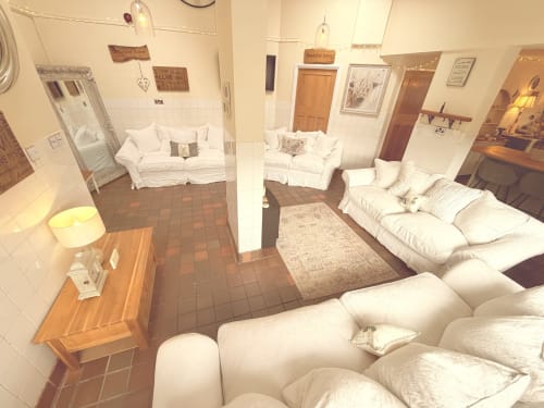 Spacious self-catering apartment at The Usk Guest House in Brecon with white sofas, wooden furniture, and terracotta floors.