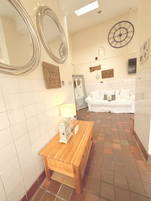 The Usk Guest House apartment in Brecon with wooden furniture, white tiled walls, decorative mirrors, and a white sofa