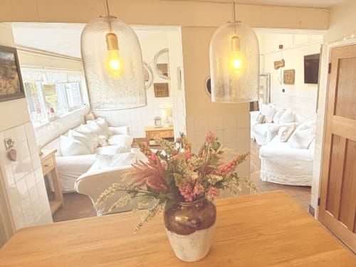 The Usk Guest House luxury apartment dining area with wooden table, pink flowers, glass pendant lights, and bedroom views in