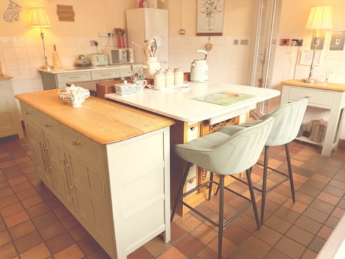 Modern kitchen with white cabinetry, wooden countertops, and bar seating at The Usk Guest house in Brecon