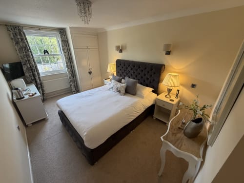 Luxury bedroom at The Usk Guest house in Brecon with dark headboard bed, white bedding, twin lamps, and mountain views
