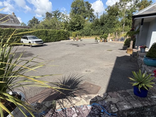 Spacious courtyard at The Usk Guest house in Brecon with parked car, potted plants, and modern facilities
