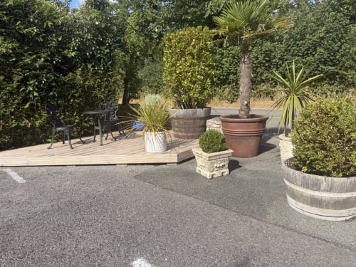 Luxury garden patio at The Usk Guest house in Brecon with wooden deck, seating, potted palms, and lush green hedges