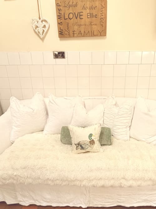 Luxurious bed at The Usk Guest house in Brecon with white pillows, cream bedding, and decorative cushions against shiplap