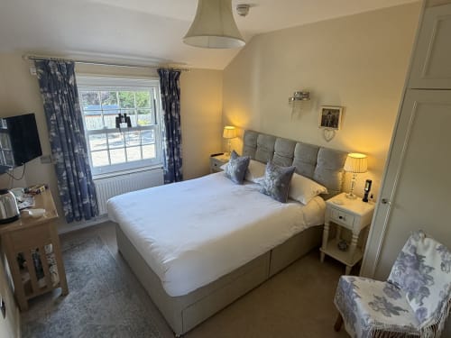 Bright bedroom at The Usk Guest House in Brecon with king bed, mountain views, twin lamps, and blue patterned curtains.