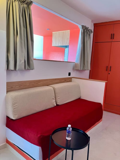 Chambre moderne à SAMYAflat Tanger avec canapé beige, tapis rouge, téléviseur mural et armoire rouge
