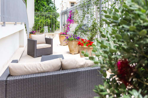 Terrazza soleggiata dell'appartamento Otranto Oasis con mobili in vimini, fioriere colorate e edera rampicante a Otranto,