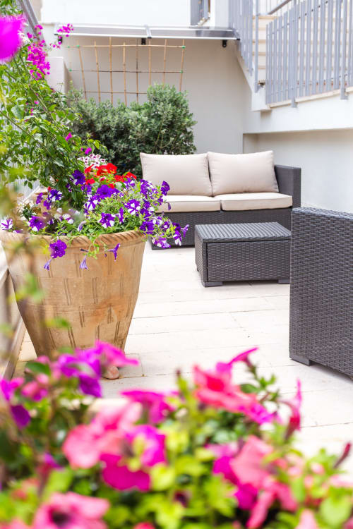 Patio colorato dell'Otranto Oasis con fiori vivaci, sedute in rattan e mobili in vimini moderno.