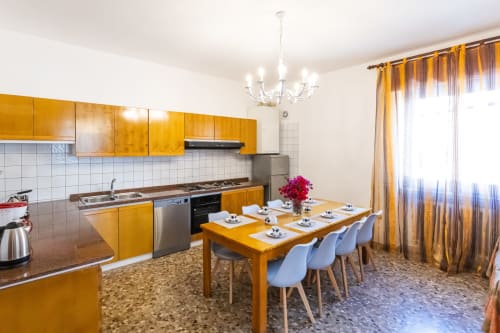Ampia zona cucina-pranzo nell'appartamento Otranto Oasis con mobili dorati, tavolo da pranzo e elettrodomestici moderni