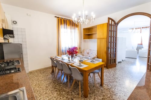 Sala da pranzo dell'appartamento con 2 camere presso Otranto Oasis con tavolo in legno, sedie moderne e vista sulla cucina