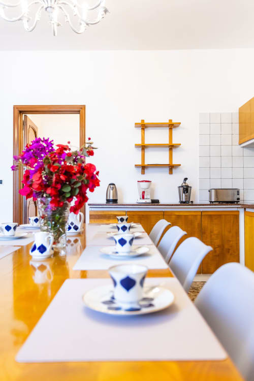 Luminosa zona cucina-pranzo dell'Otranto Oasis con fiori freschi, sedie bianche, mobili in legno e elettrodomestici in acciaio inox
