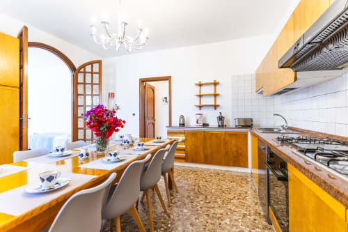 Luminosa zona cucina-soggiorno con mobili gialli, piastrelle bianche, tavolo da pranzo e cucina a gas nell'Otranto Oasis.