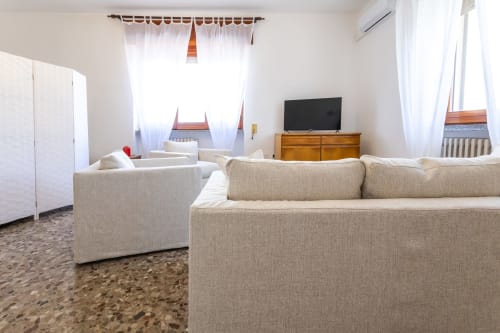 Luminoso soggiorno moderno con divani color crema, mobile TV in legno e guardaroba bianco nell'Oasi di Otranto in Italia