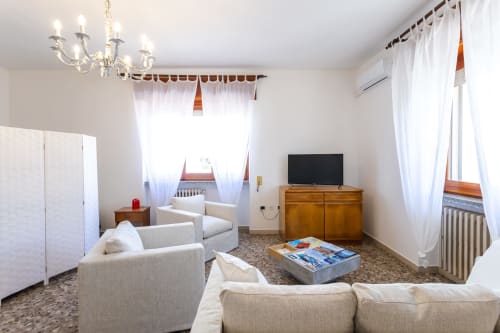 Ampio soggiorno nell'appartamento di Otranto con comodi sedili, TV, mobili in legno e finestre luminose
