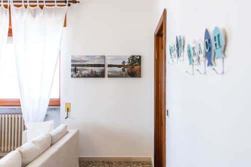 Camera da letto moderna in Otranto con tendaggi bianchi, quadri paesaggistici, decori marini e porta in legno