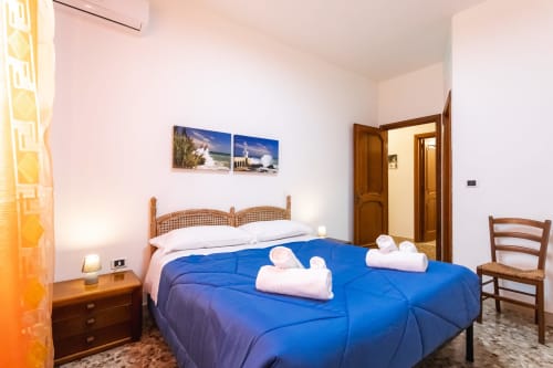 Camera luminosa all'Oasi di Otranto con piumone blu, letto in legno, cuscini bianchi e illuminazione calda a Otranto, Italia