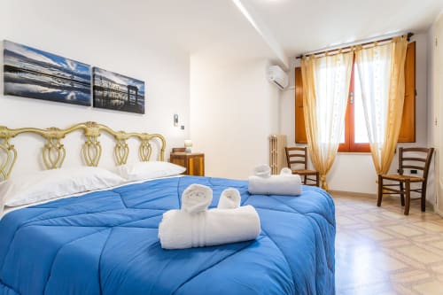 Camera spaziosa presso Otranto Oasis con piumone blu, testata ornamentale dorata, asciugamani bianchi e tende gialle.