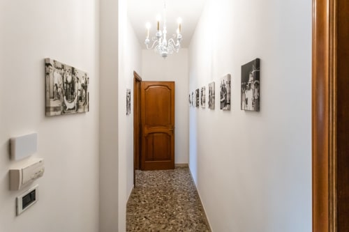 Elegante corridoio dell'Otranto Oasis con pareti bianche, pavimenti in cotto, porta in legno, fotografie vintage e