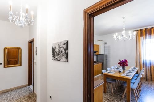 Elegante sala da pranzo nell'appartamento di Otranto con tavolo in legno, sedie blu, lampadario e centrotavola floreale