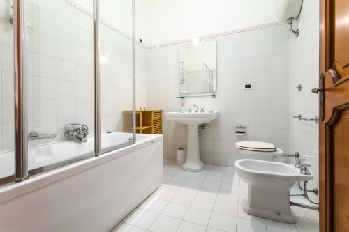 Bagno luminoso all'Otranto Oasis con vasca, bidet, lavabo con colonna, specchio e piastrelle bianche