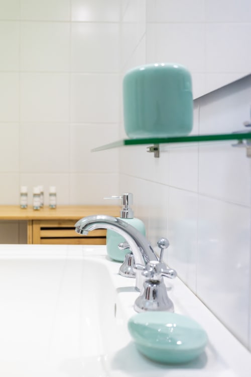 Bagno moderno all'Oasi di Otranto con dispenser azzurro, rubinetto cromato e piastrelle bianche in appartamento 2 camere.