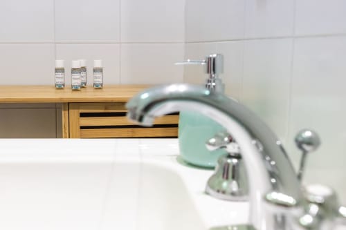 Lavabo del bagno con rubinetto verde menta e articoli da toilette all'appartamento Otranto Oasis in Italia