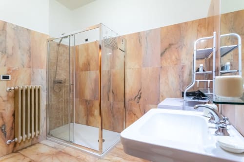 Bagno moderno dell'appartamento Otranto Oasis con pareti in marmo, doccia in vetro e doppio lavabo