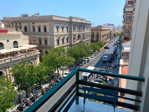 Vista dal balcone del centro storico di Palermo con edifici neoclassici e strada alberata da BnB del Parlamento