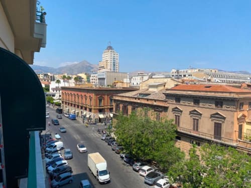 Vista dal balcone del centro storico di Palermo con edifici colorati, auto parcheggiate e il Monte Pellegrino in lontananza