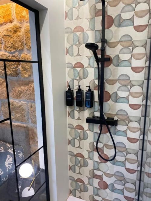 Bagno moderno con doccia in Palermo BnB: fixture nere, piastrelle geometriche, box doccia in vetro con finestra vista città