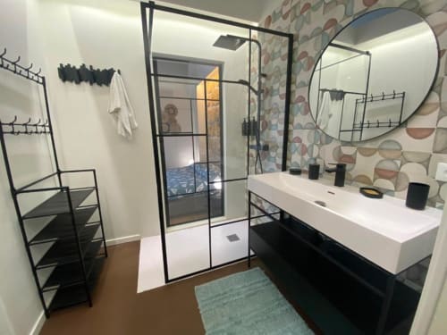 Bagno moderno nell'appartamento di Palermo con doccia walk-in, vanity bianca, specchio rotondo e parete con piastrelle geometriche