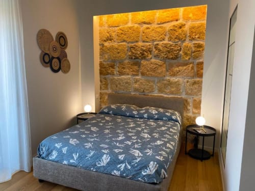Camera moderna presso BnB del Parlamento Palermo con biancheria azzurra decorata, muro in pietra, pavimento in legno e elementi decorativi
