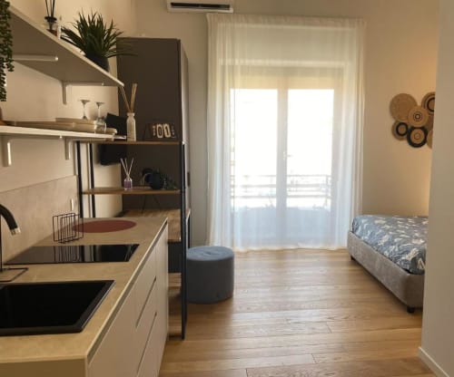 Modern studio con angolo cottura, letto, scaffali e accesso al balcone con luce naturale presso BnB del Parlamento Palermo