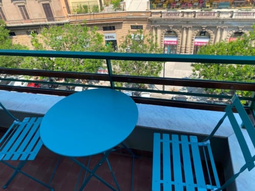 Arredamento blu in esterno su un balcone con vista sui palazzi storici e i cortili verdi di Palermo presso BnB del Parlamento.