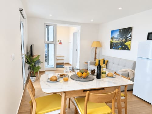 Modern open-plan dining and living area at Sunshine House 85, Check Madeira villa in Ribeira Brava with marble table, yellow