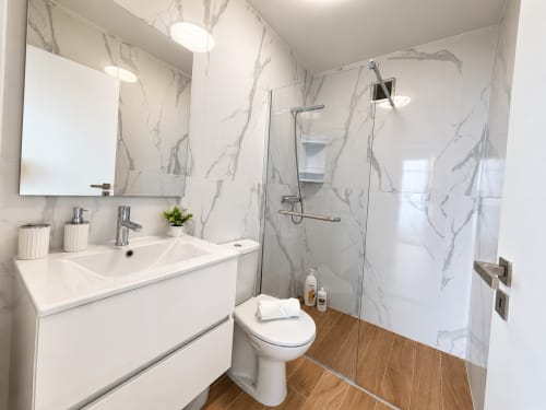 Modern bathroom in Sunshine House 85 villa at Check Madeira with marble-effect tiles, white vanity, toilet, and walk-in