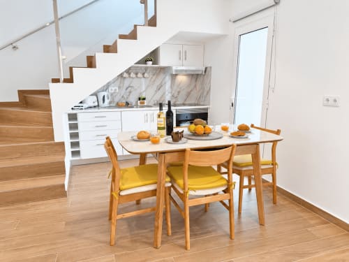 Modern kitchen-dining area in Sunshine House villa, Ribeira Brava, with wooden dining table, yellow chairs, and marble